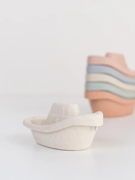 cream wheat straw boat in front of a stack of colorful boats