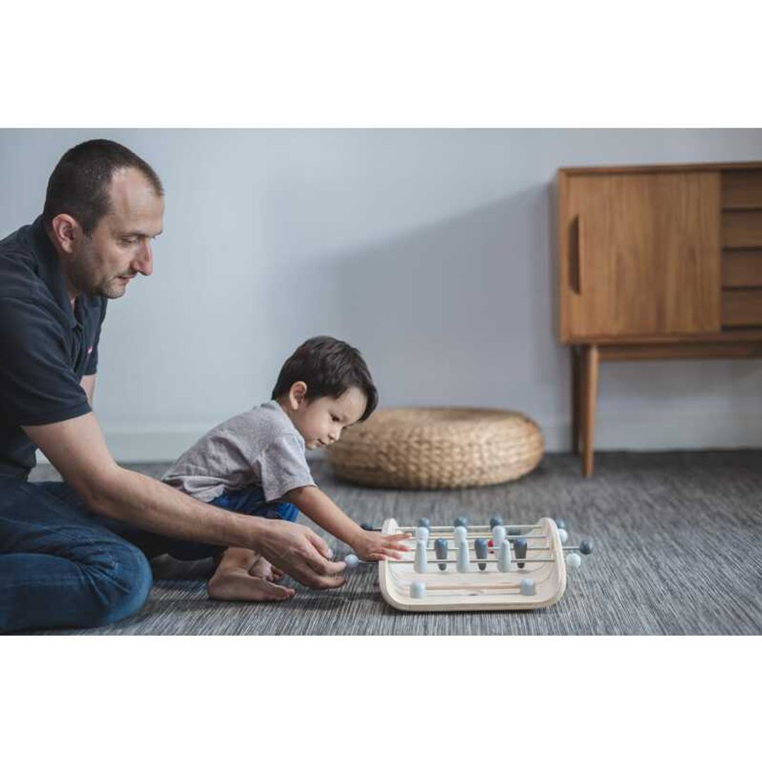 parent and child playing with Soccer by Plan Toys