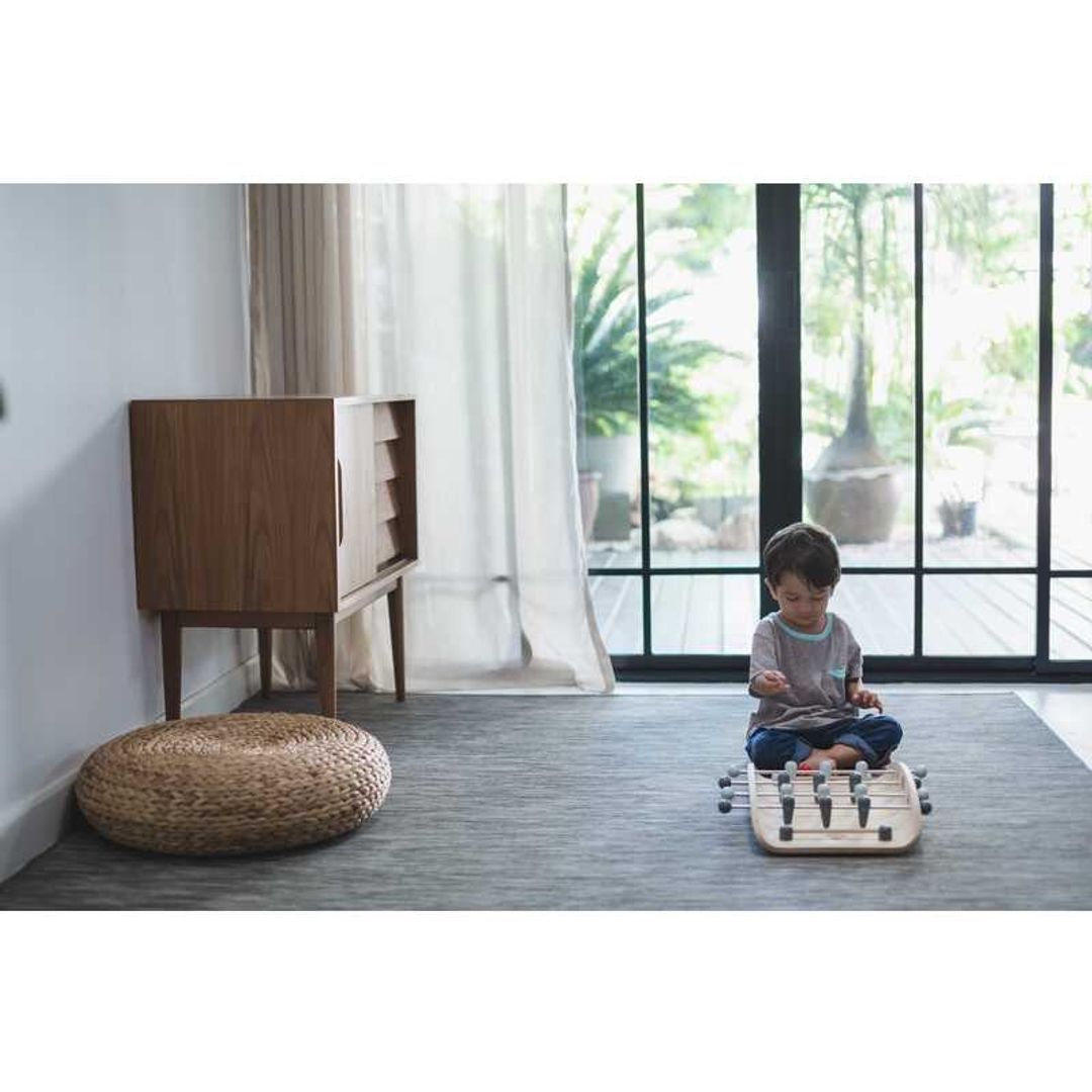 kid playing with a wood soccer game by Plan Toys