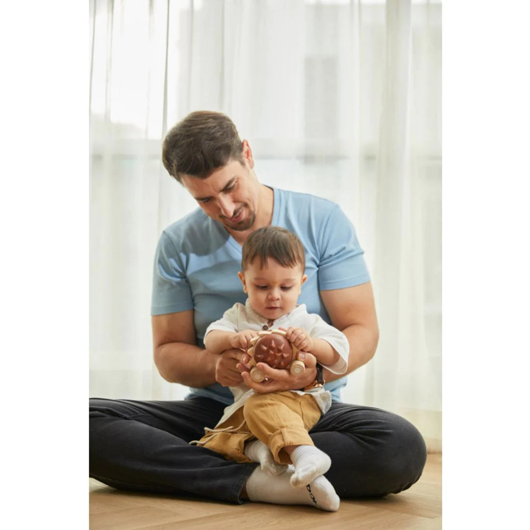 Parent and child playing with brown pull-along hedgehog