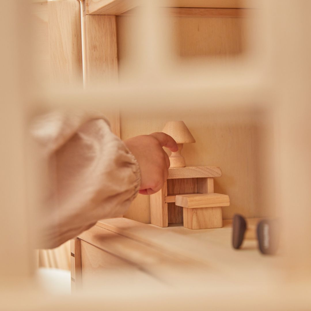 Child playing with a Victorian Dollhouse by Plan Toys