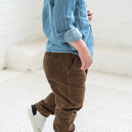 a child walking wearing sepia corduroy pants and a denim shirt