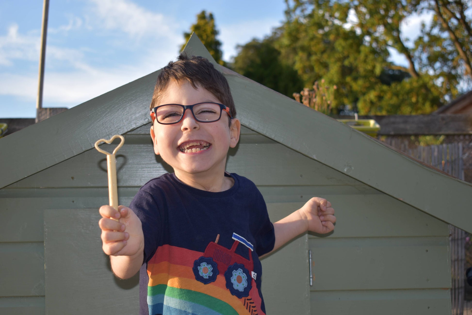 a young child standing outdoors holding a mini bubble wand