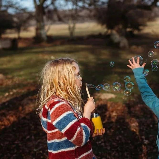 a child standing outside blowing bubbles with a mini bubble kit