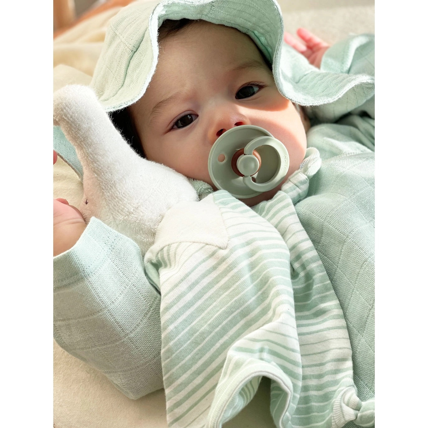 Baby in a Organic Sea Breeze Poplin Sun Hat with pacifier in their mouth