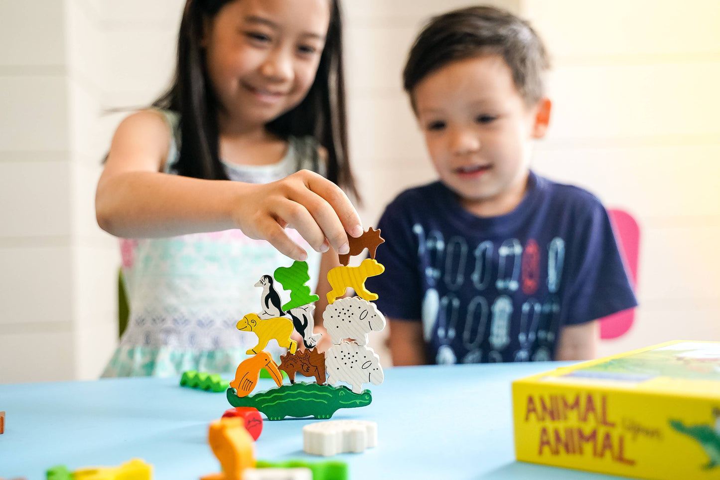 two kids playing Haba Stacking animal game animal upon animal at a table