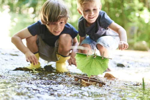 Two children playing with Terra Cork Boat in a stream