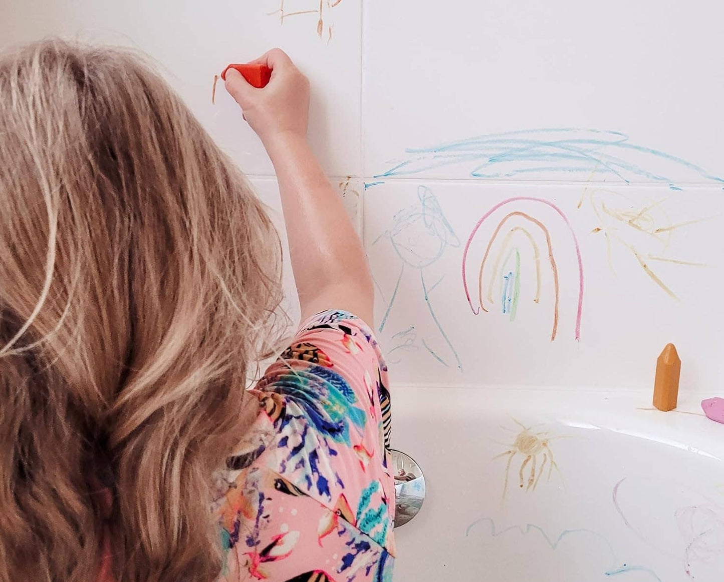 child drawing on a bathtub with triangle bath crayons