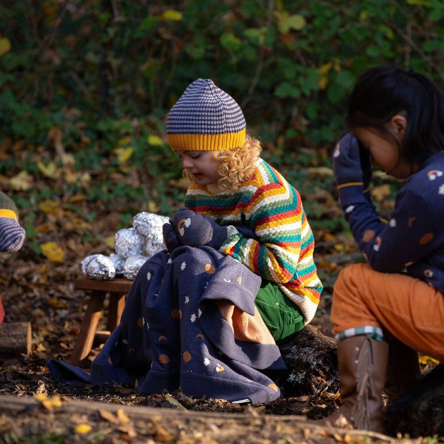 children sitting outside in the woods wearing outfits and accessories by Little Green Radicals