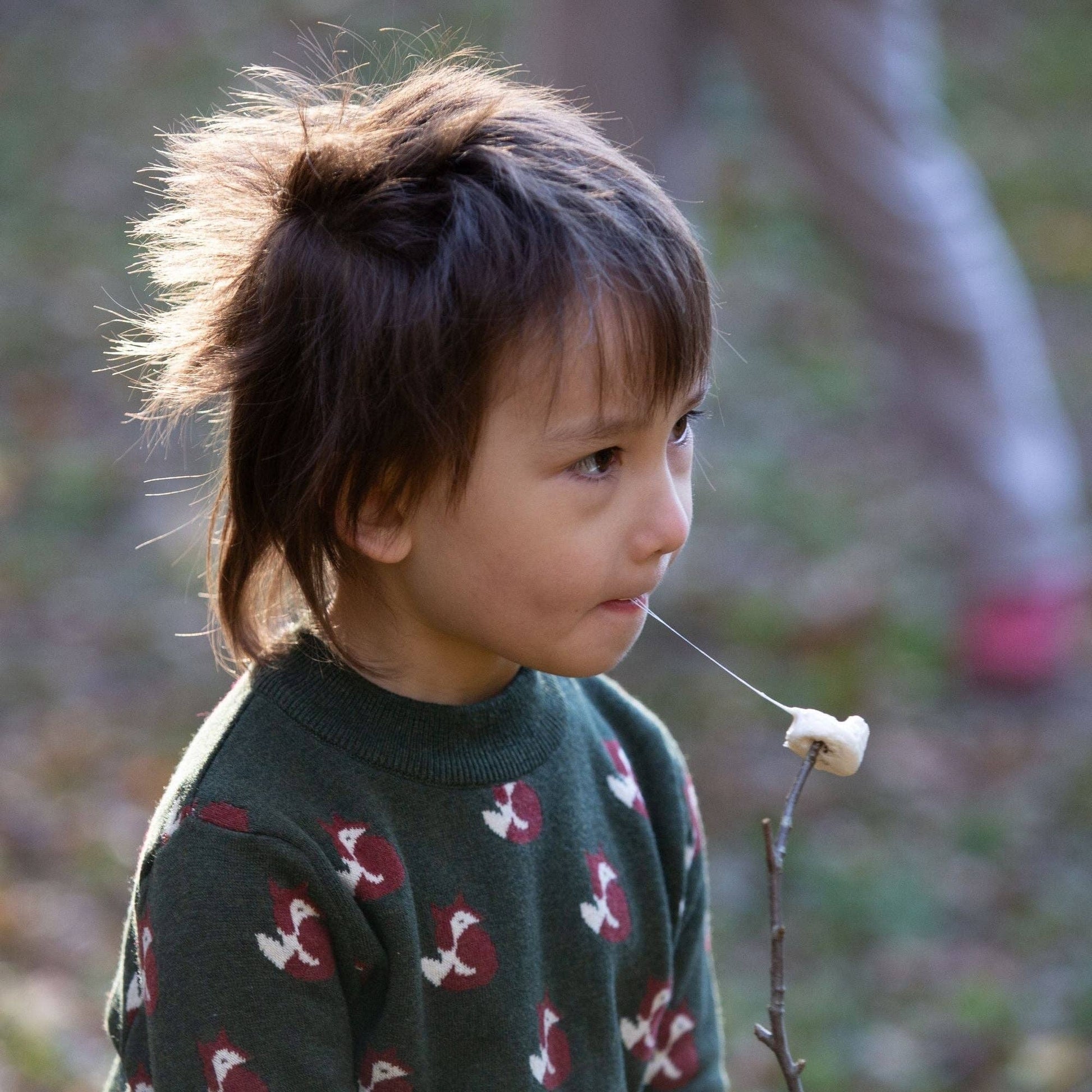 child standing outside eating a s'more wearing little foxes organic sweater