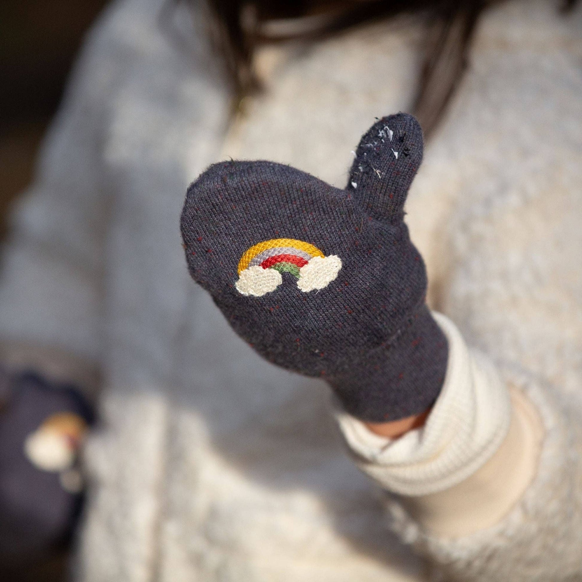 close-up of a child's hand with a blue knitted mitten on