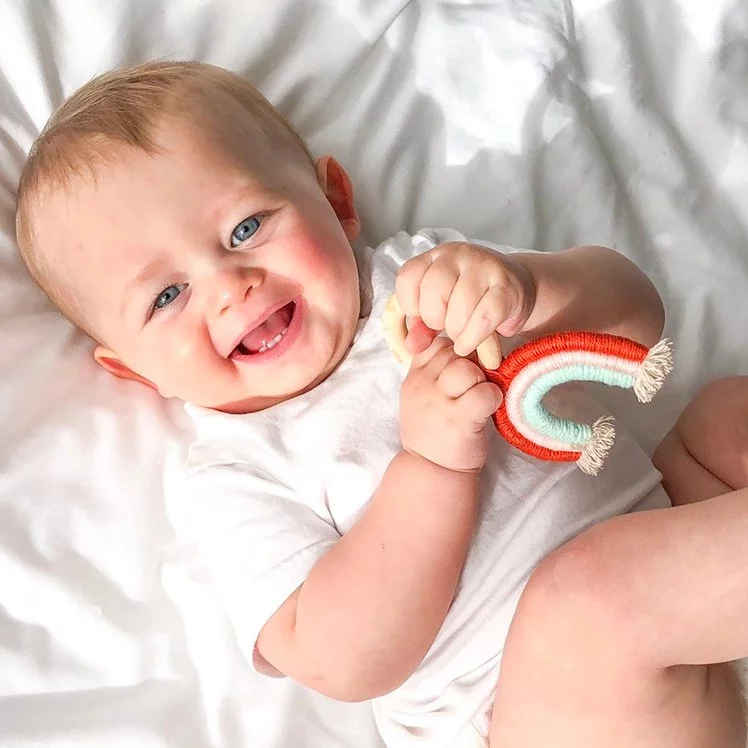 Baby holding mini rainbow teether by Mama Siesta