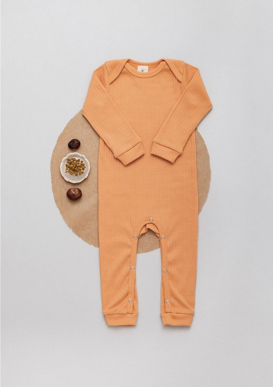 Long sleeve ribbed romper in ochre laid flat next to chestnuts