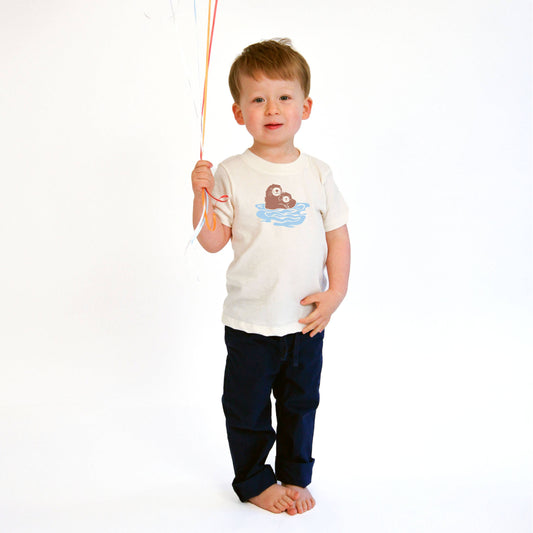 a child holding balloons on a string wearing a short sleeve organic cotton tee with a mom and baby otter design