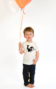 Child holding balloons wearing orcas organic kids tee