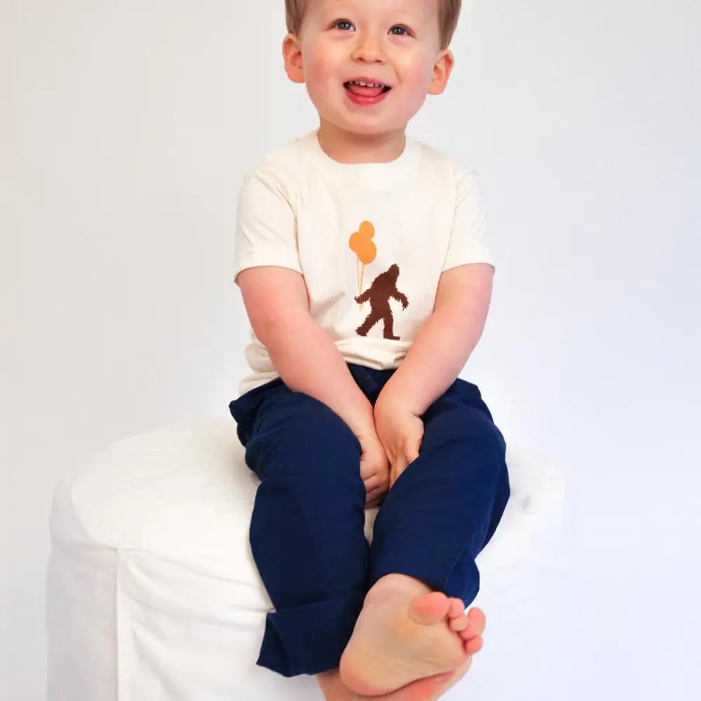 child sitting down wearing organic Sasquatch & balloons tee