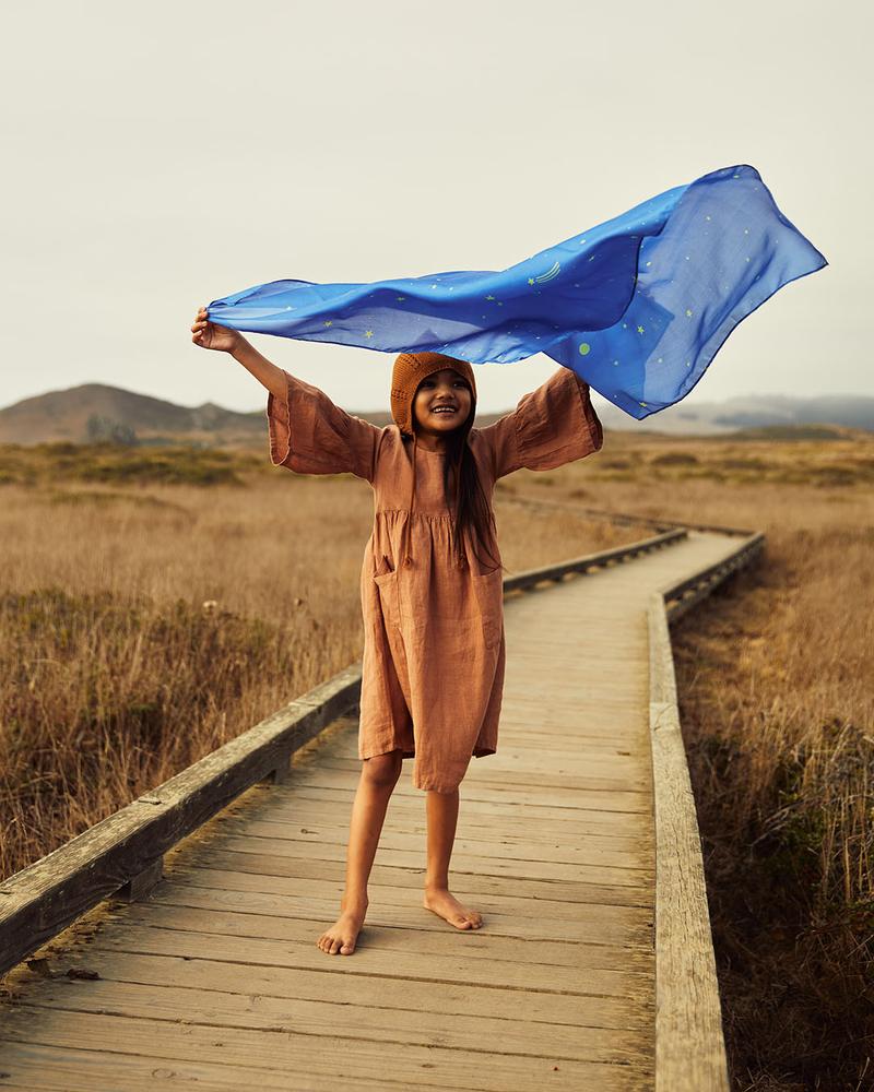 child standing on a boardwalk playing with starry night playsilk