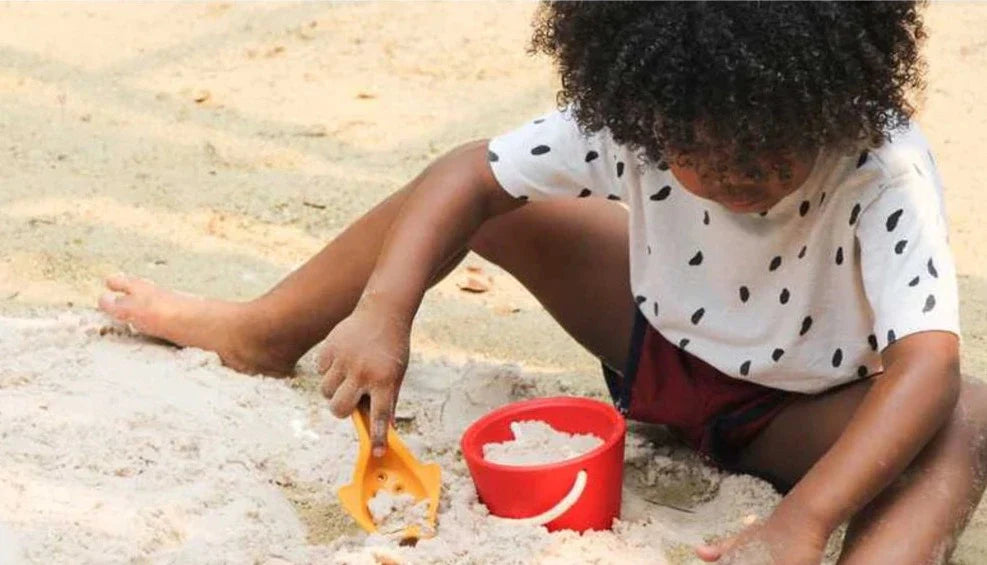 child on the beach playing with sand play set