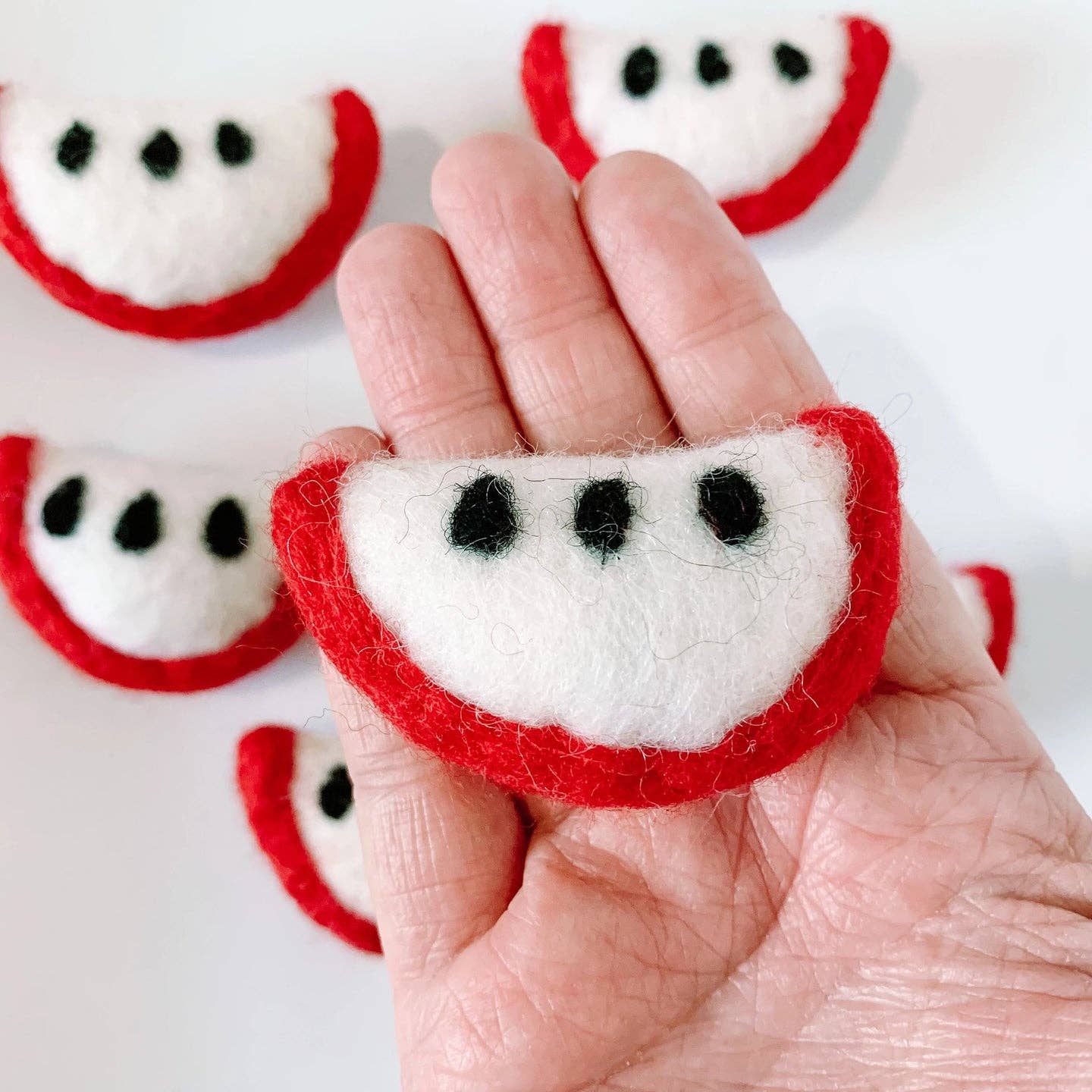 hand holding a red felt apple slice