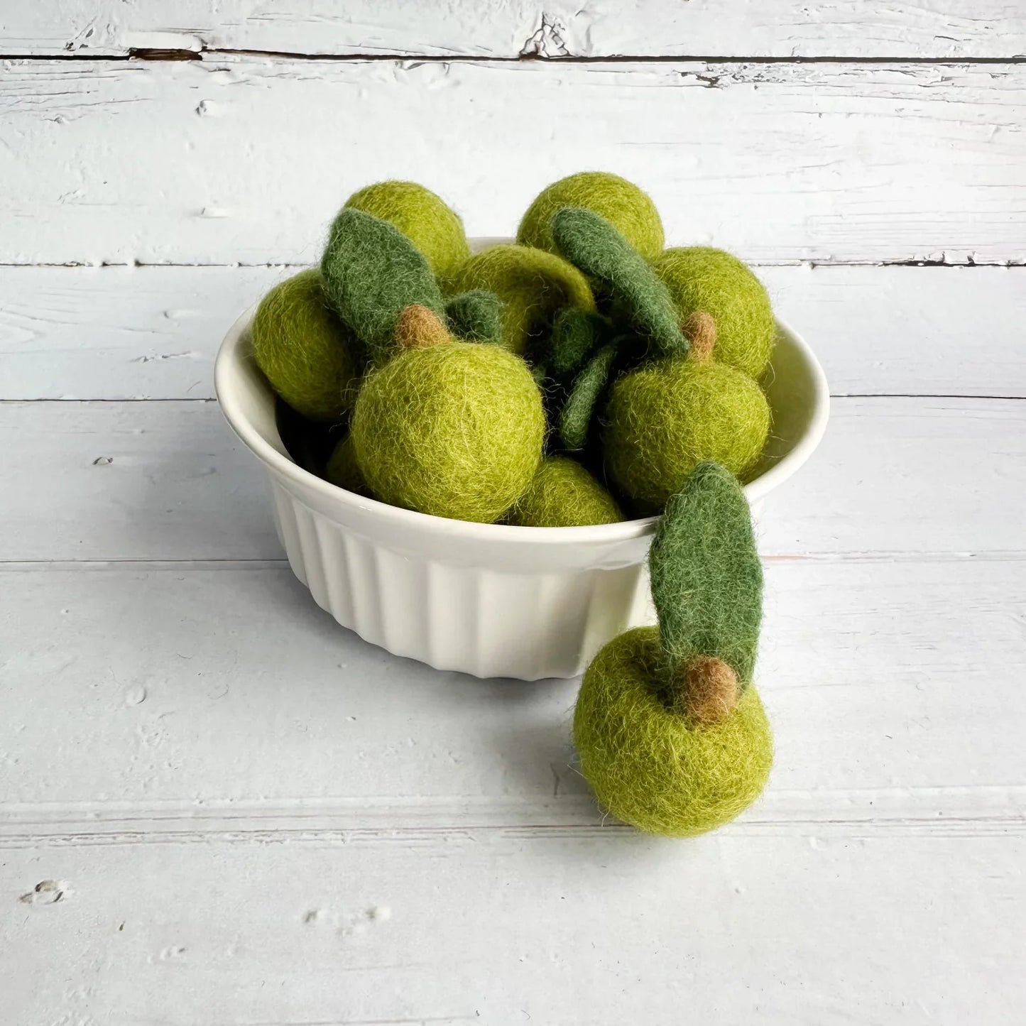 green mini felt apples in a white bowl