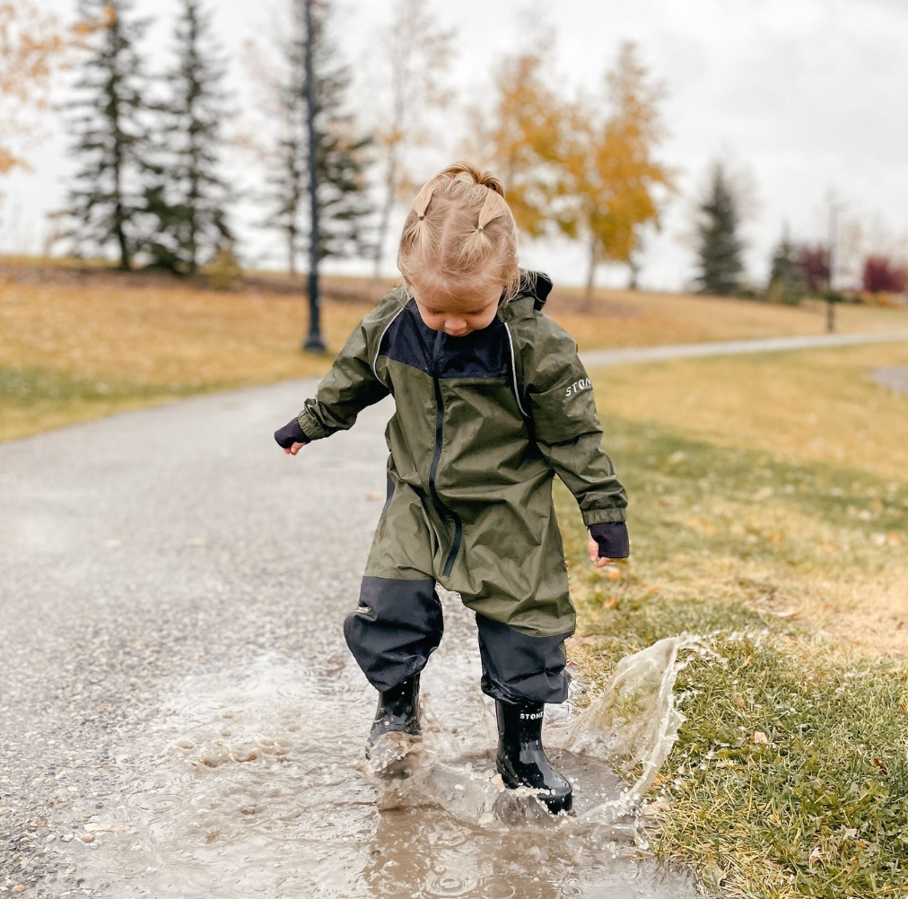 Child splashing in a puddle wearing a cypress rainsuit