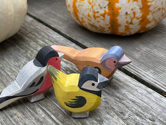 3 hand carved hand painted finches by ostheimer toys on a weathered wood with striped pumpkins int he back ground