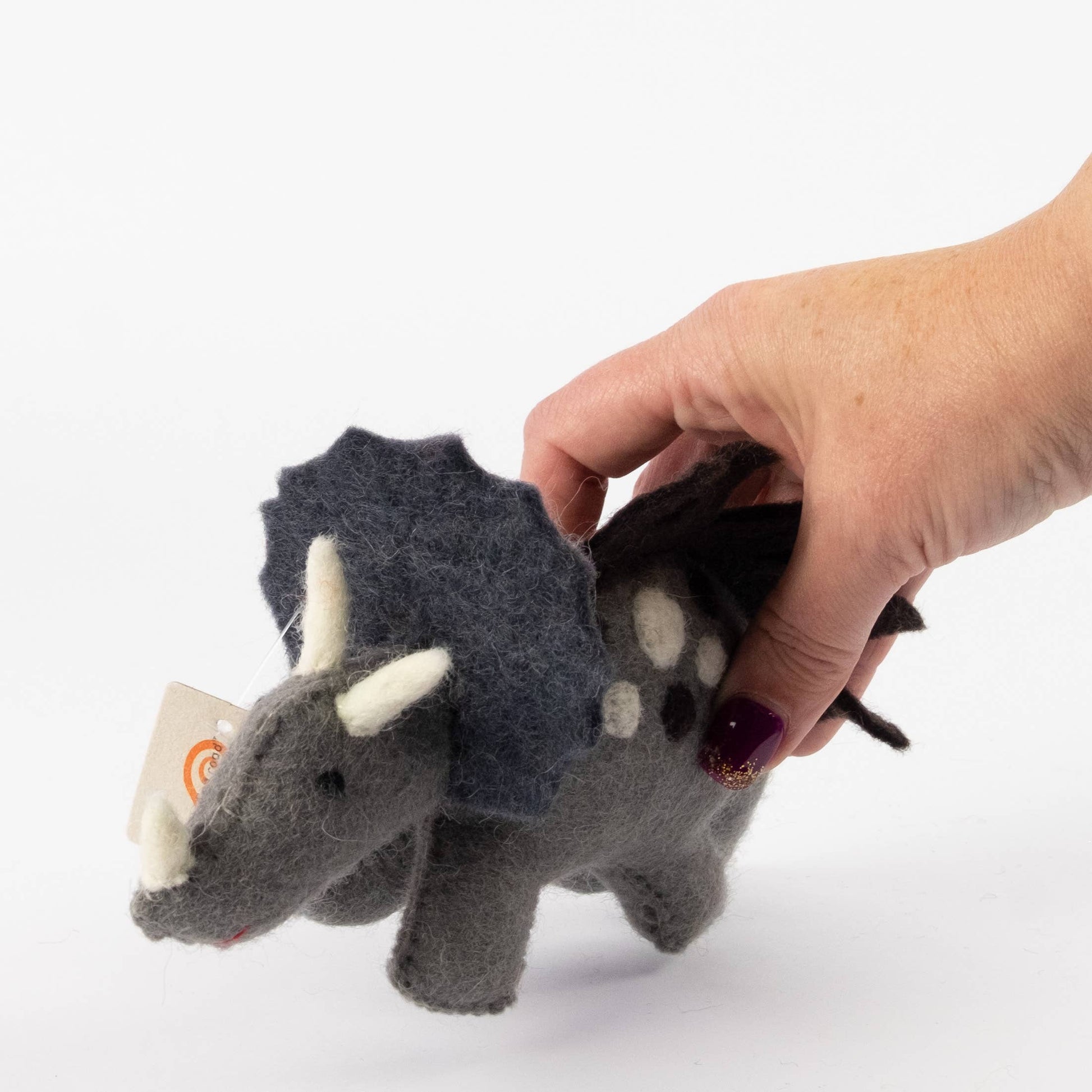 a hand holding a felt triceratops