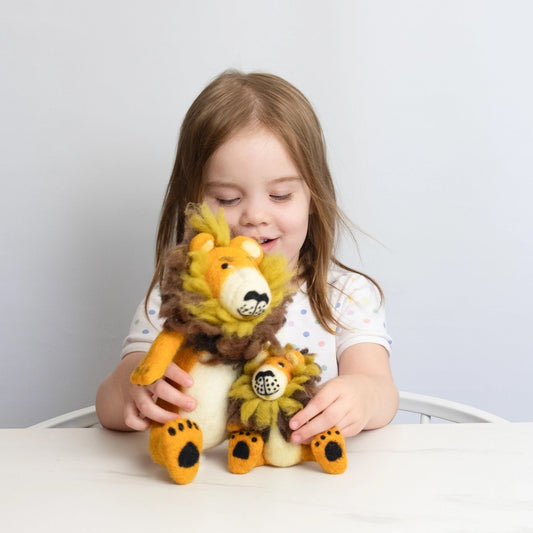 child playing with two felt lions, one small and one large, on a white table