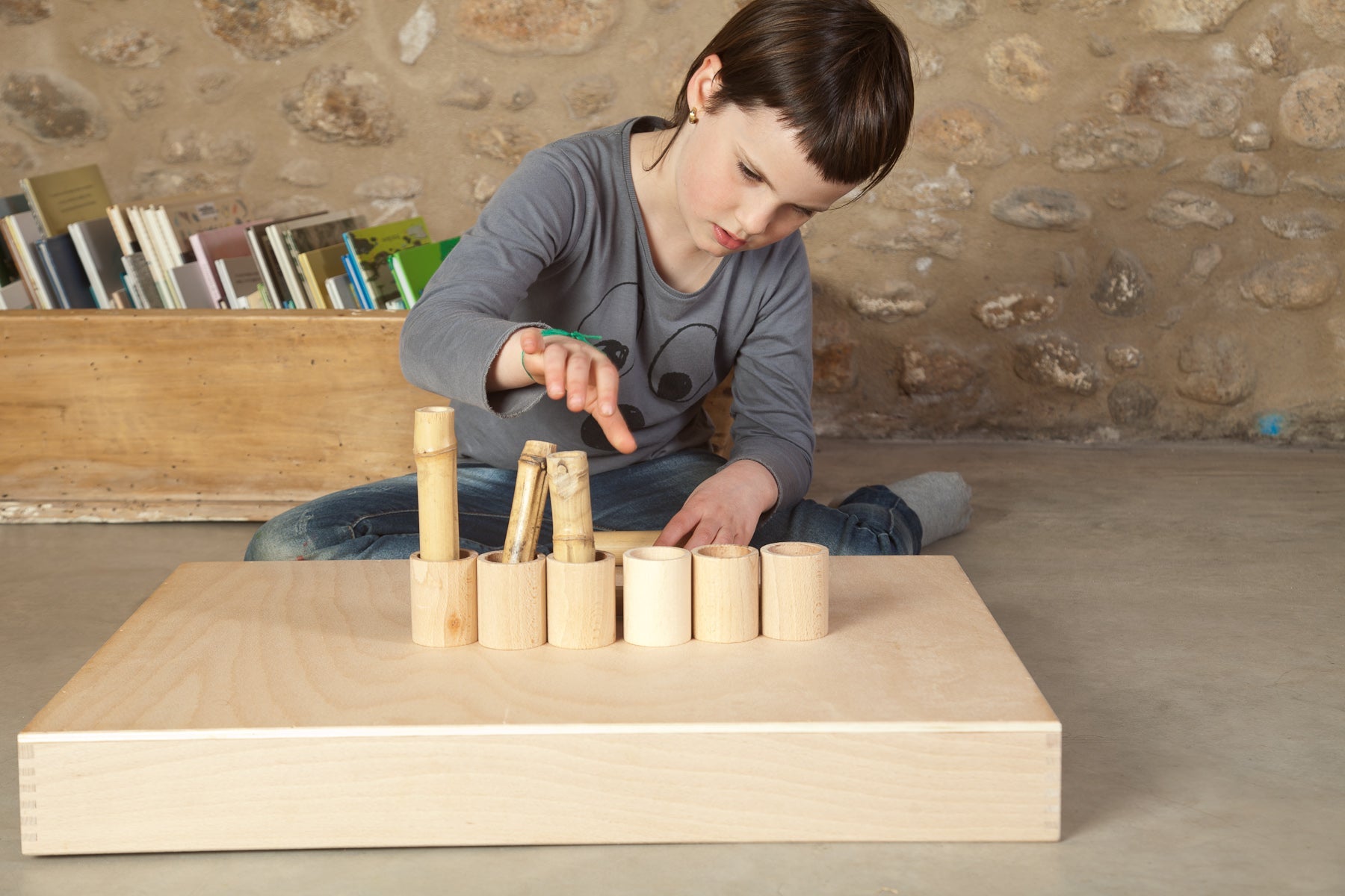 Child filling natural cups with bamboo sticks