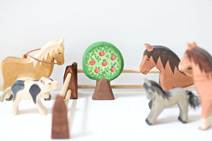 ostheimer brown horses grey pony and a spotted pig with stable gates and an apple tree
